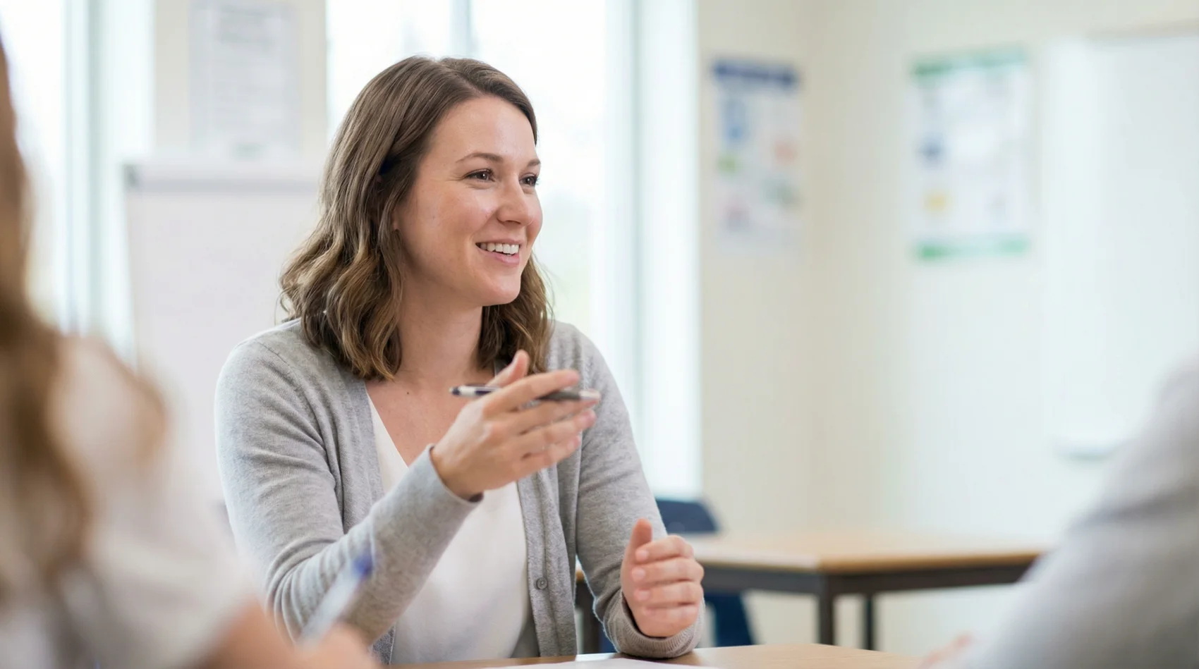 Studentin nimmt an einem Elite Tutor Kurs teil, hört aufmerksam zu und macht Notizen in einem hellen Lernraum.